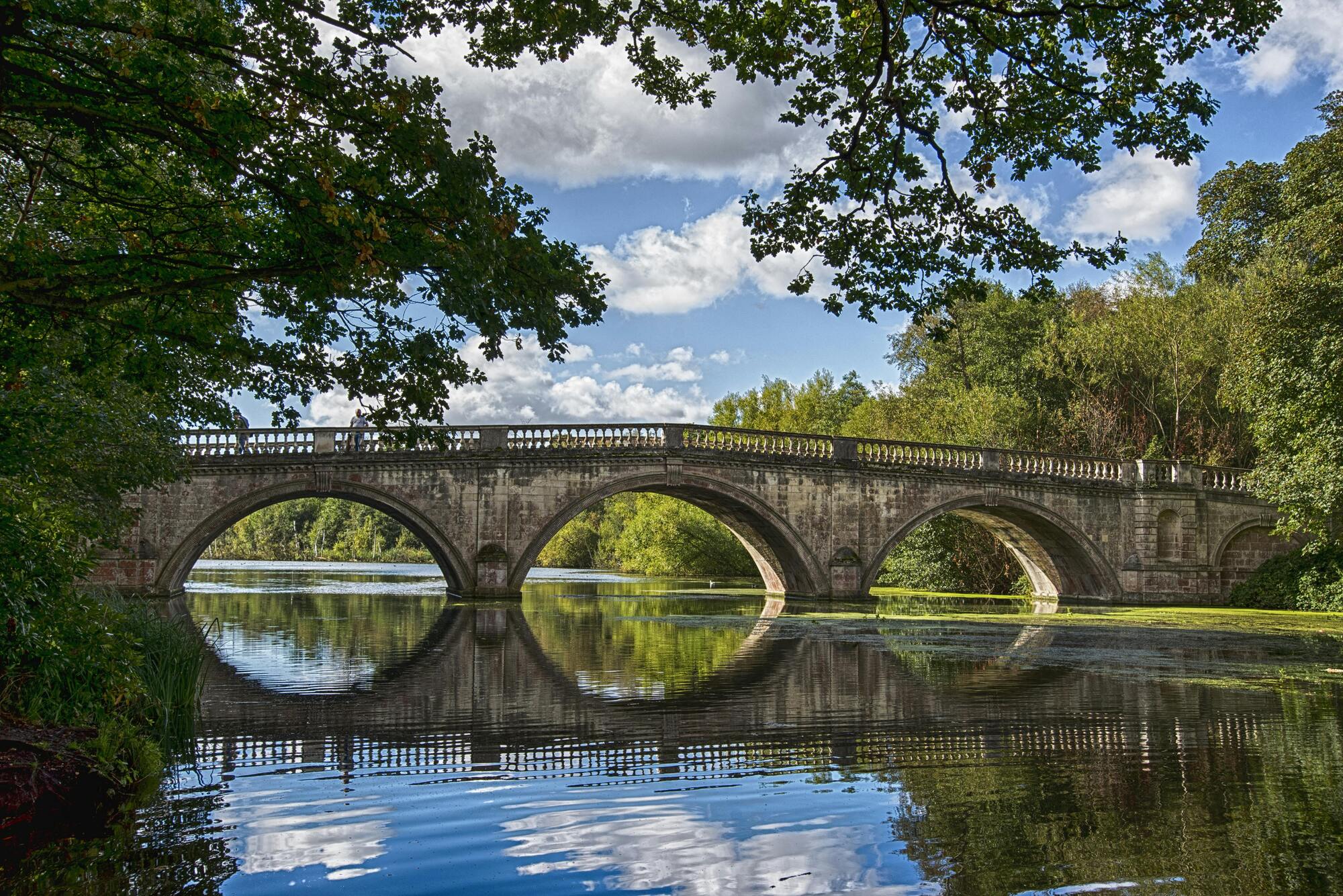 Stone arch bridge reflected in still water